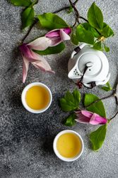 Top view of magnolia flowers with green tea and teapot