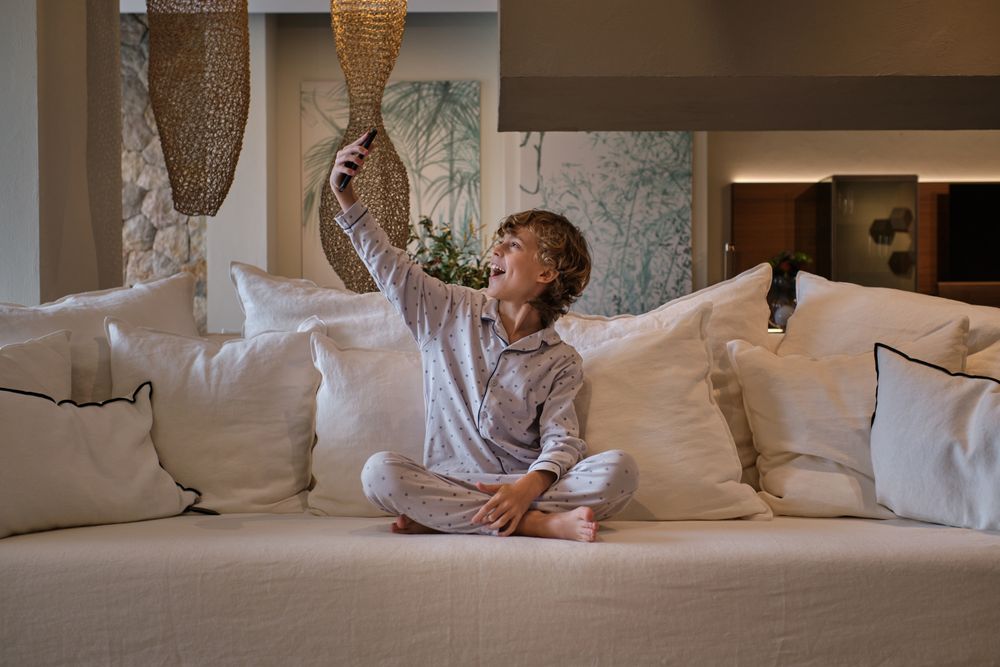Excited boy taking selfie on sofa at home
