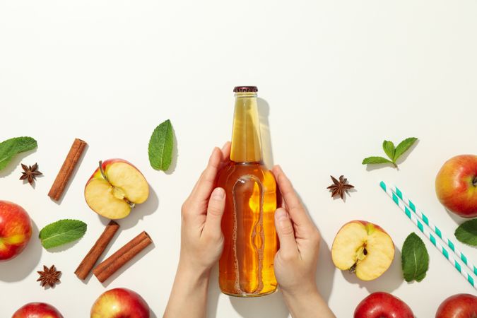 Female hands hold bottle of cider on light background. Composition with cider