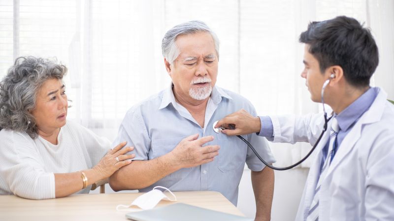 Doctor with stethoscope on worried Asian male patient’s chest