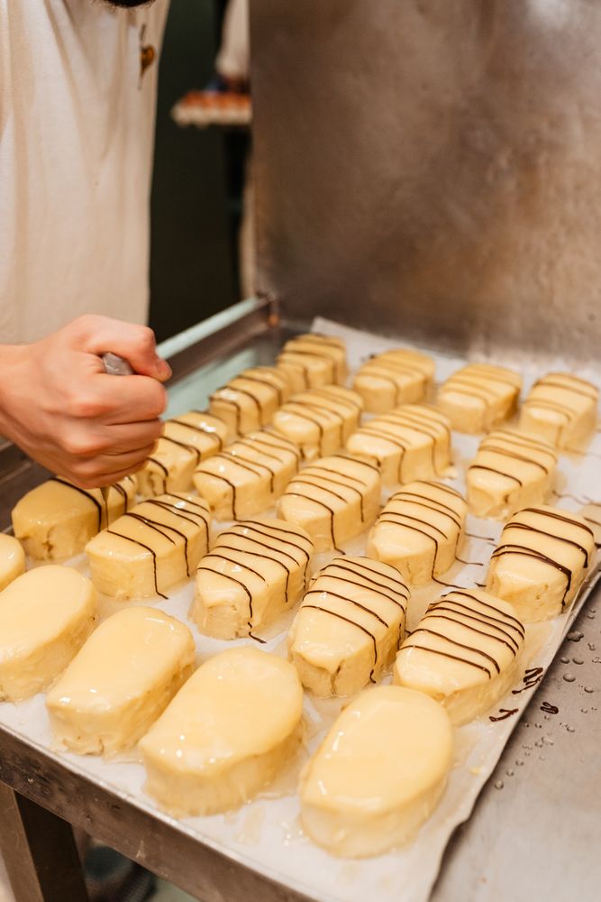 Crop confectioner decorating pastry with chocolate cream