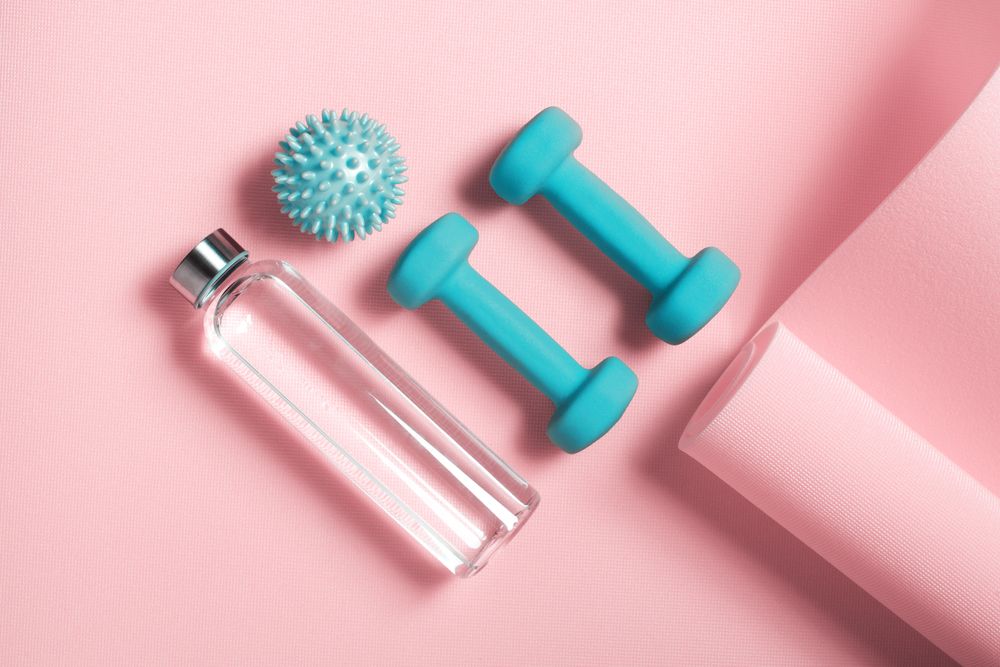 Top view of colorful weights, yoga mat and water