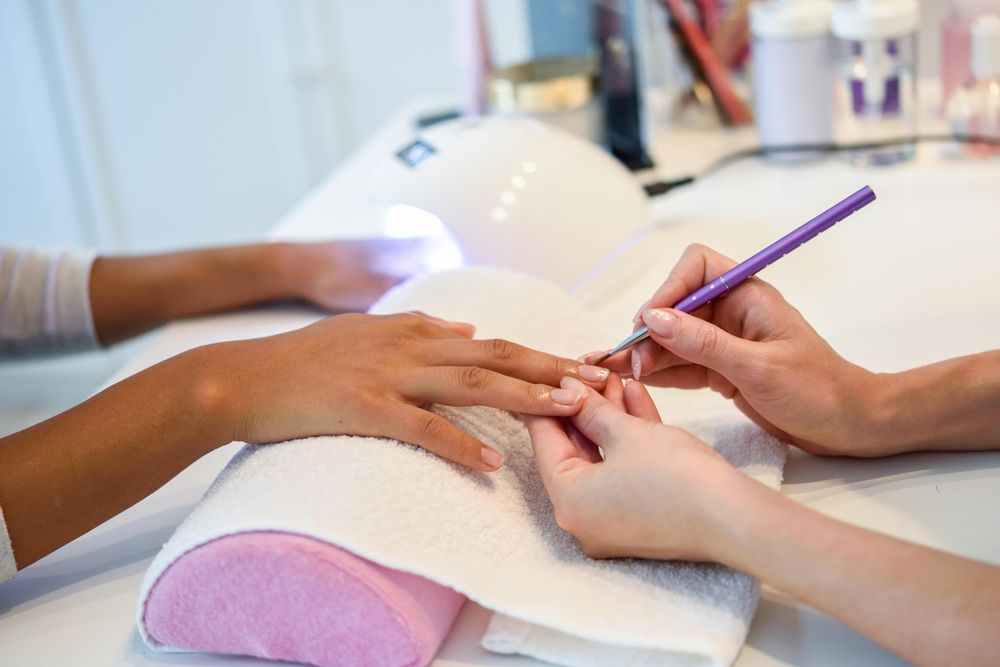 Close-up of beautician painting a woman's nails with nail varnish