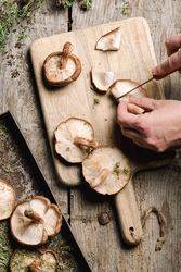 Person preparing fresh brown mushrooms for cooking