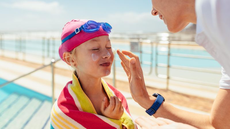 Mother adding sunscreen to her daughter’s face