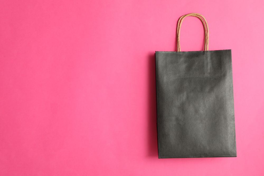 dark paper bag on pink background, space for text