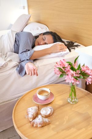 Female sleeping on bed near table with coffee cup