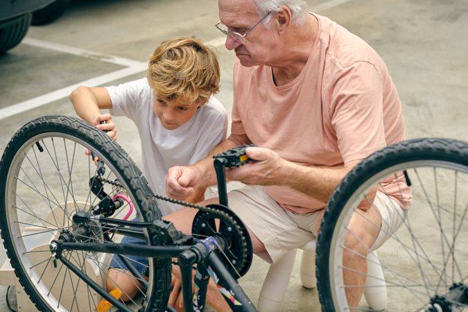 Mature man and grandson during repairing of bicycle wheel
