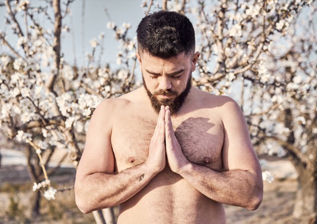 Shirtless man meditating in spring garden