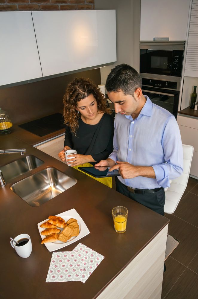 Top view of couple looking at tablet while having coffee in home before work