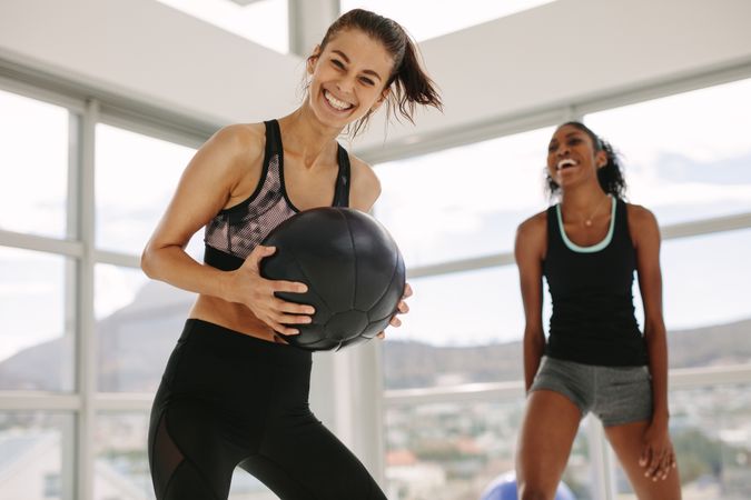 Smiling women working out in fitness studio with medicine ball