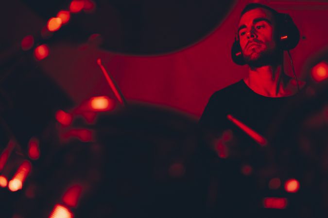 Man with drumsticks playing on drums in redness