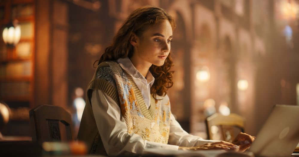 Serene Young Woman Studying With Laptop in a Vintage Library, Surrounded by Books and Warm Lighting.