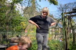 Woman looking over boy in garden