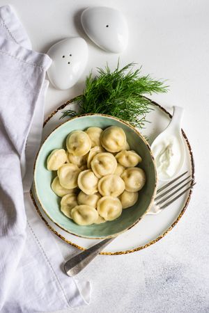 Top view of bowl of comforting Russian dumplings with salt and pepper shakers