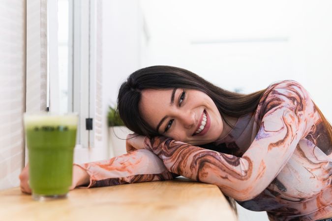 Content woman enjoying green beverage in bar