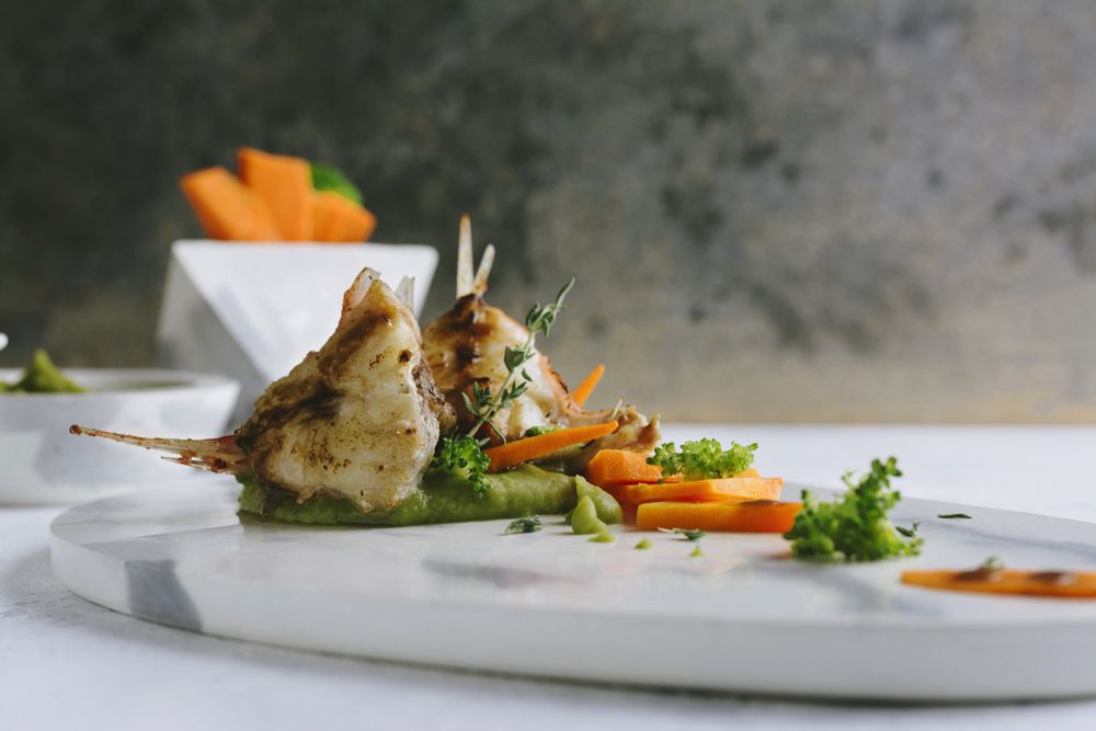 grilled scorpion fish with mashed peas and carrot sticks, on a marble plate