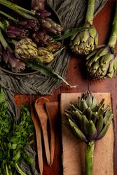 Fresh artichokes and parsley on table