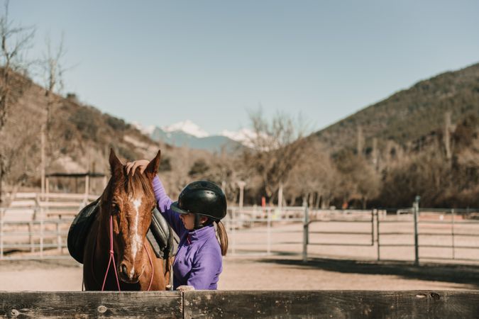 Young woman petting horse in enclosure