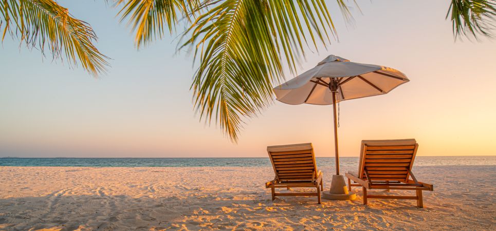 Two lounge chairs on an idyllic tropic beach, wide shot