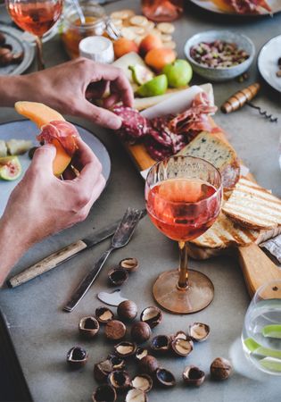 Charcuterie, with wine and snacks, man with prosciutto and melon with hazelnuts