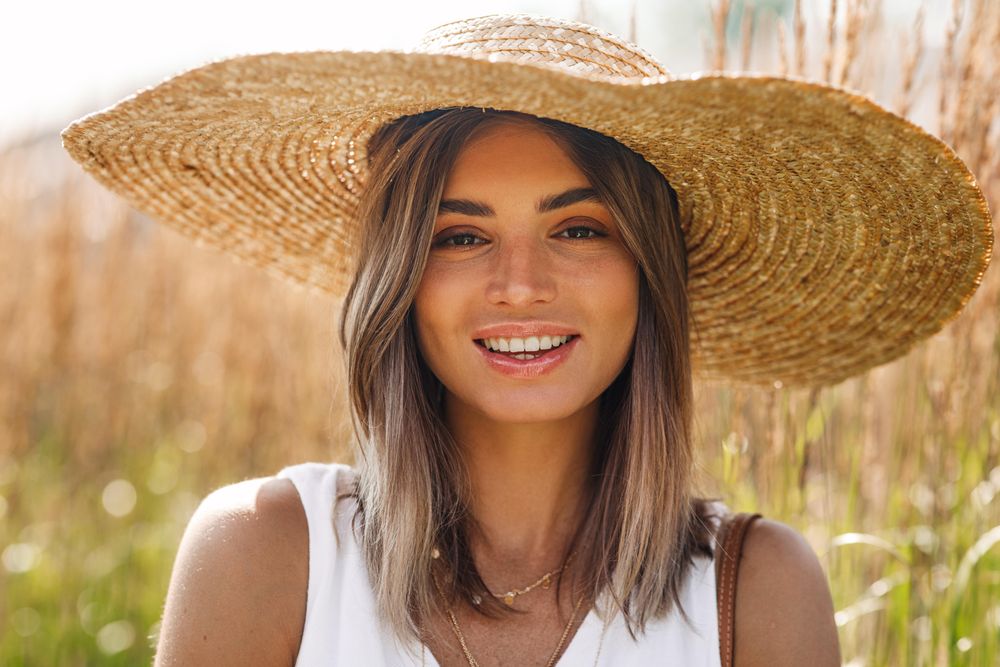 Content woman in field with straw hat