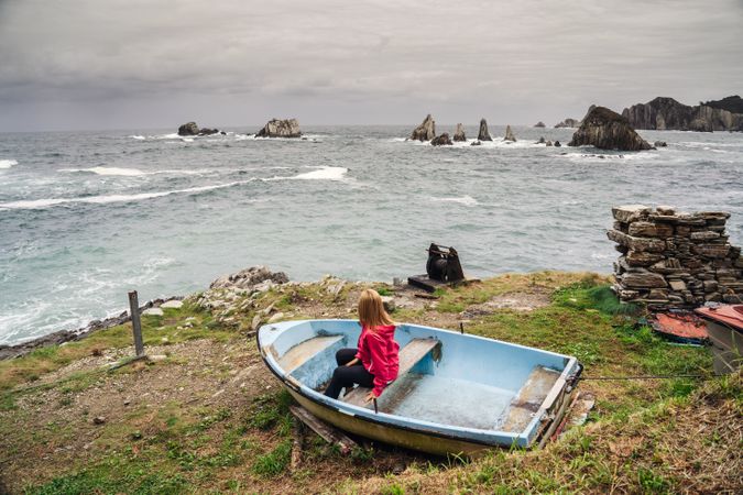 Woman in old blue on seashore washing by foamy waves