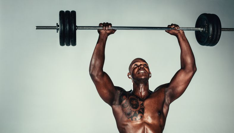 Muscular Black man exercising with barbell