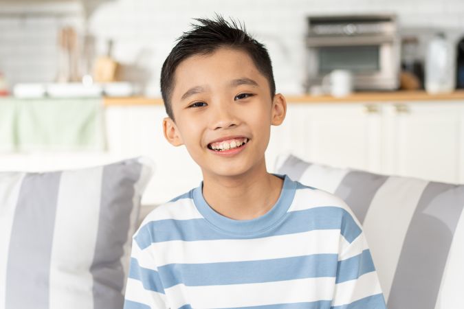 Portrait of Asian boy sitting on couch in the living room looking at camera