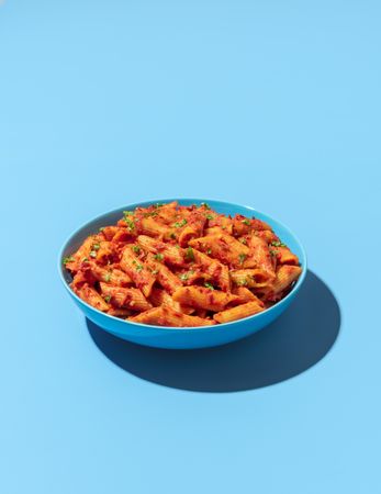 Penne pasta bowl isolated on a blue background