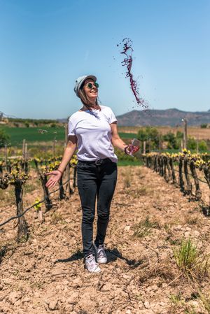 Excited woman spilling red wine from glass in hands