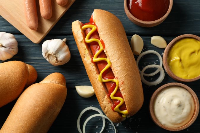 Tasty hot dog and ingredients on wooden background