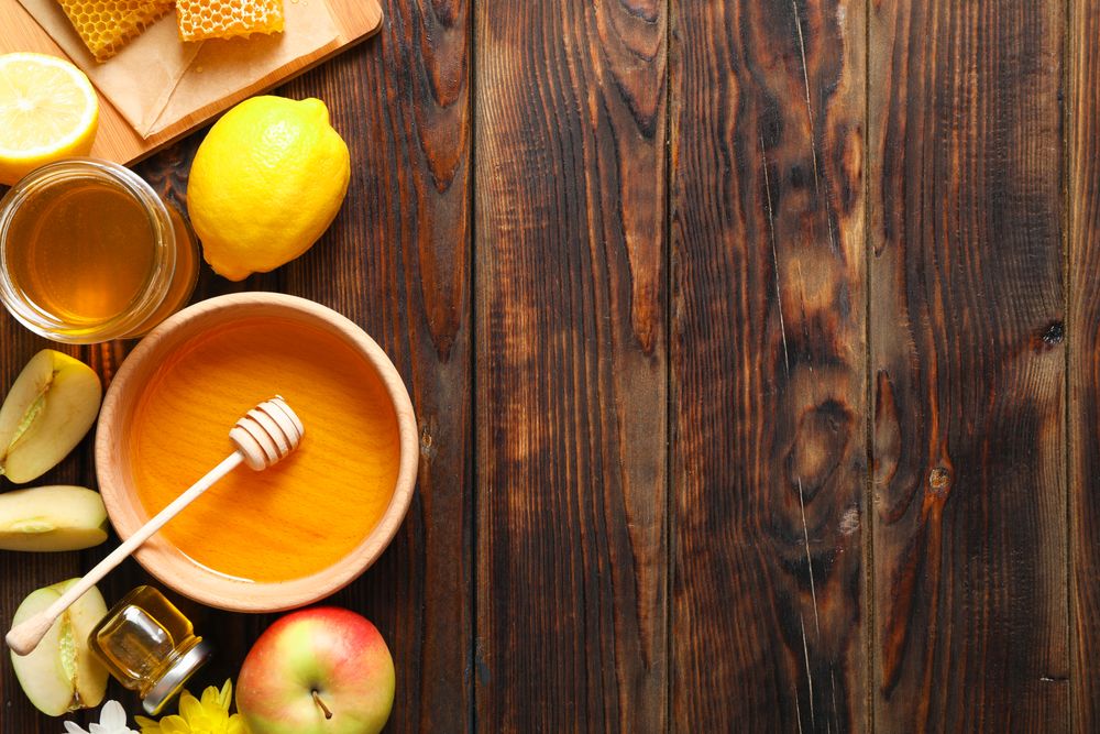 Flat lay with honey, flowers and fruits on wooden background, space for text