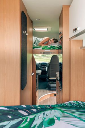 Female napping in motorhome bunk bed, vertical