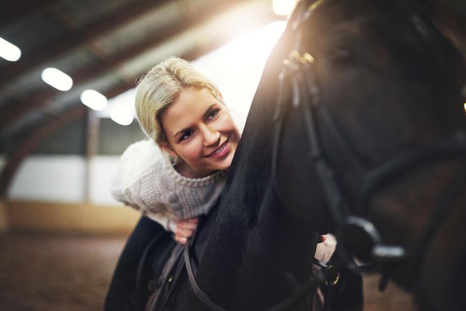 Happy horse trainer taking horse for a ride in an indoor arena