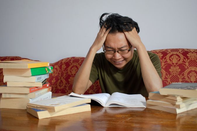 Asian young male reading book with frustrated gesture