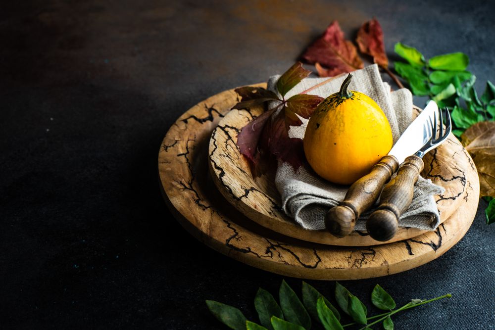 Rustic Thanksgiving table setting with squash on brown tableware with space for text