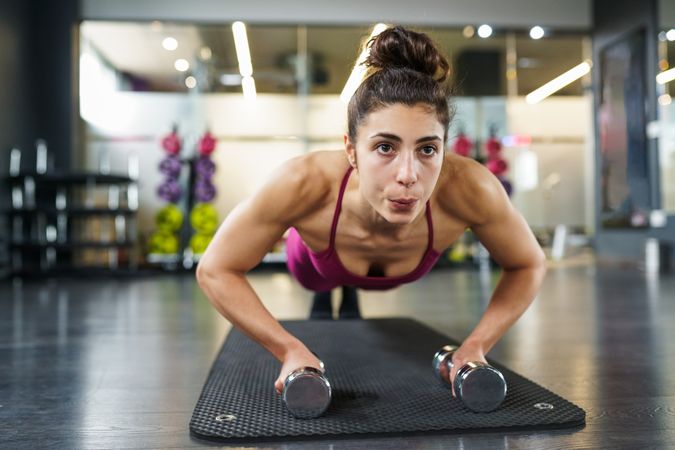 Healthy woman doing push ups while holding weights