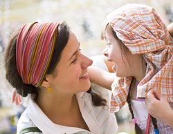 Two sisters playing outside the younger of which is laughing with a shirt on her head