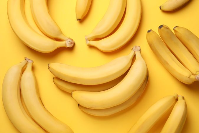 Banana clusters on yellow background. Fresh fruit