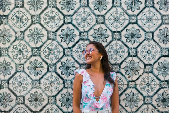 Dreamy stylish woman in sunglasses standing on city street