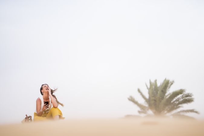Happy woman using smartphone in desert