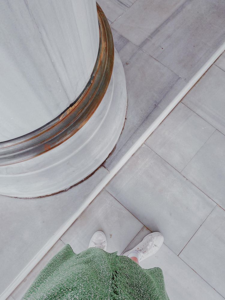 Feet standing at the bottom of marble pillar