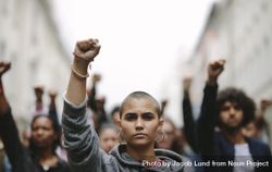 Young woman protesting on the street with her fist raised in air 0WVA6b