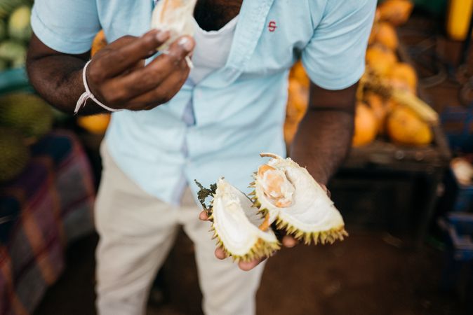Sri Lankan holding open durian fruit at market
