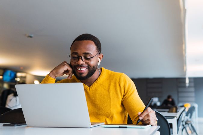 Smiling Black man working on laptop with tablet