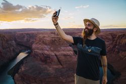 Cheerful traveler taking selfie near canyon