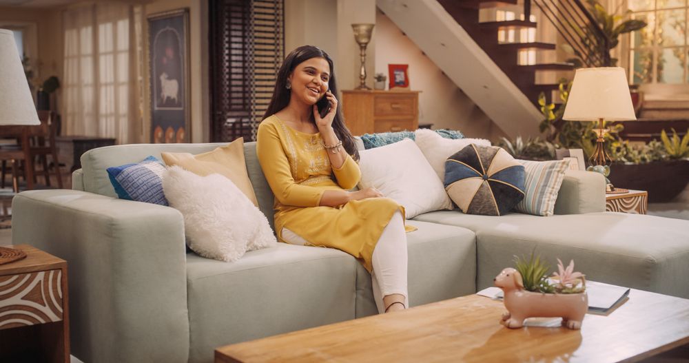 Woman Sitting On A Couch At Home, Talking on a Phone, Chatting With Her Family, Friends