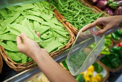 Crop buyer taking green pea pod in food store