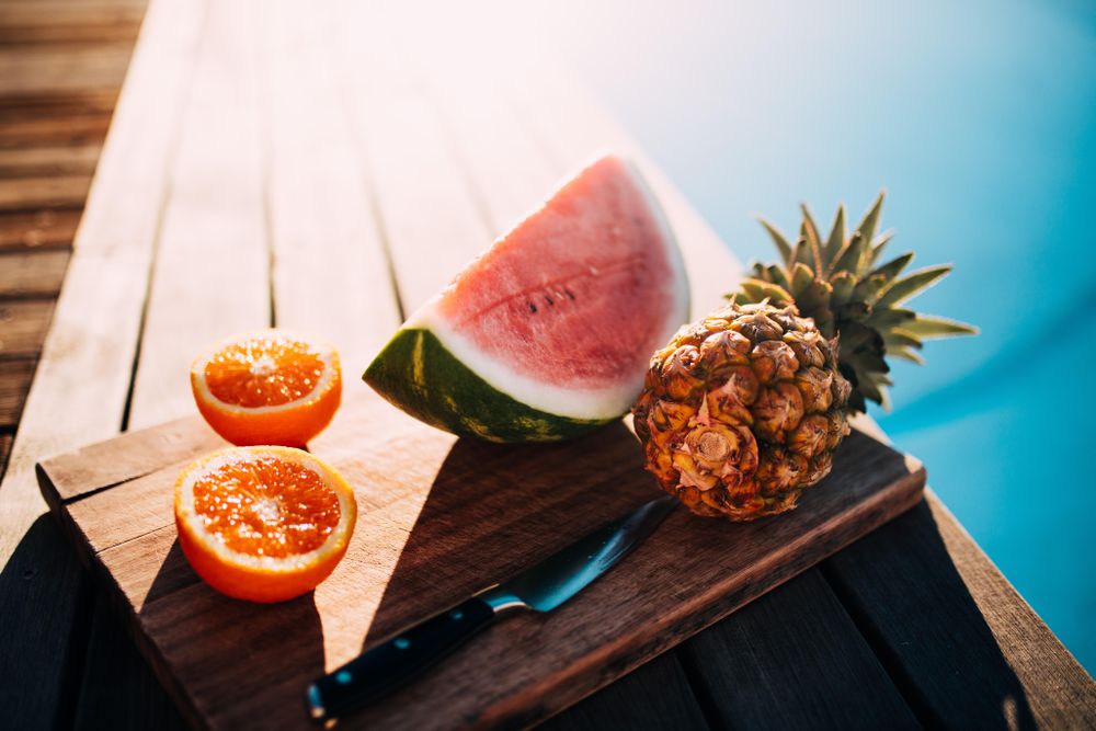 Fruit tray on a wooden board displayed by the pool on a sunny day